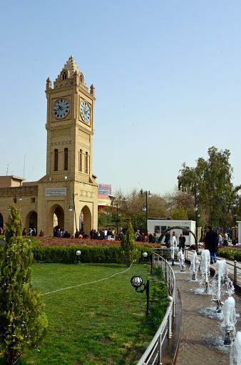 Erbil, Kurdistan, Iraq - March 10, 2013:  people pass by Erbil Clock Tower on Shar Park