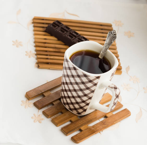 Snapshot of a coffee cup with saucer, coffee spoon, and sugar tongs with surface movement and coffee drops