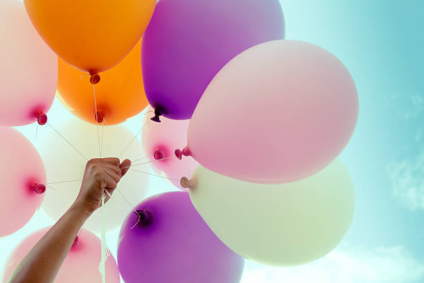 istock woman hand holding colorful balloons 497810384