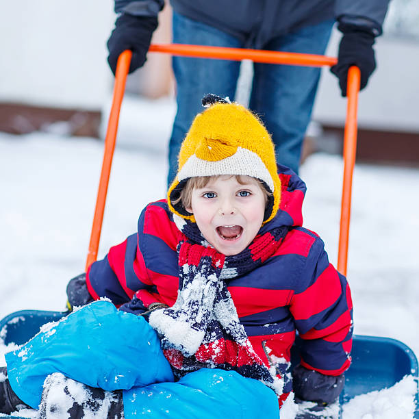 istock Funny kid boy having fun with riding on snow shovel 497812098