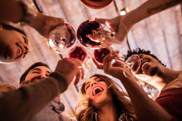 Below view of group of friends toasting with wine. Low angle view of happy start up team toasting to their success. work party stock pictures, royalty-free photos & images