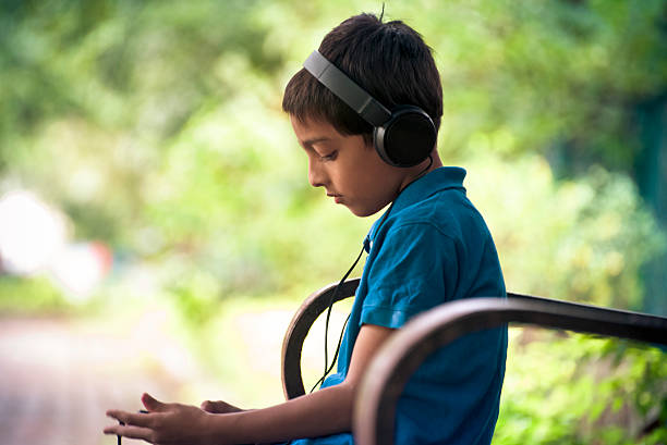 istock Boy listening to music on park bench 497814088