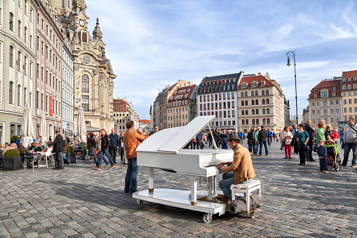 Dresden, Germany - 03 October 2015: Unidentified man plays on a white grand piano on Neumarkt square in the center of Dresden