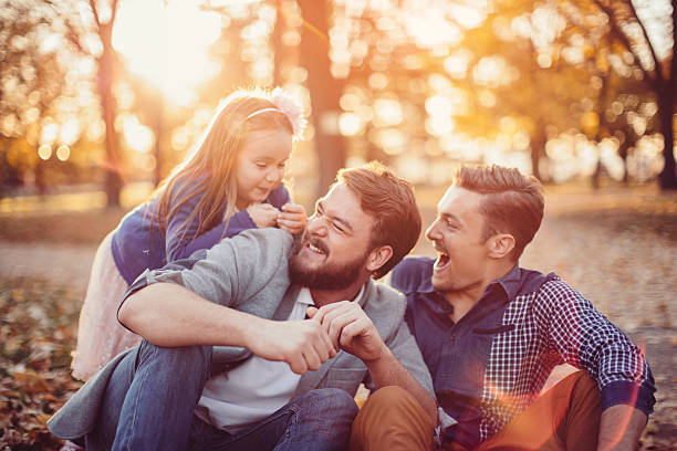 Gay Parents with daughter Young gay parents with their daughter having fun in park. Enjoying in beautiful sunny day. Caucasian ethnicity. gay daddy stock pictures, royalty-free photos & images