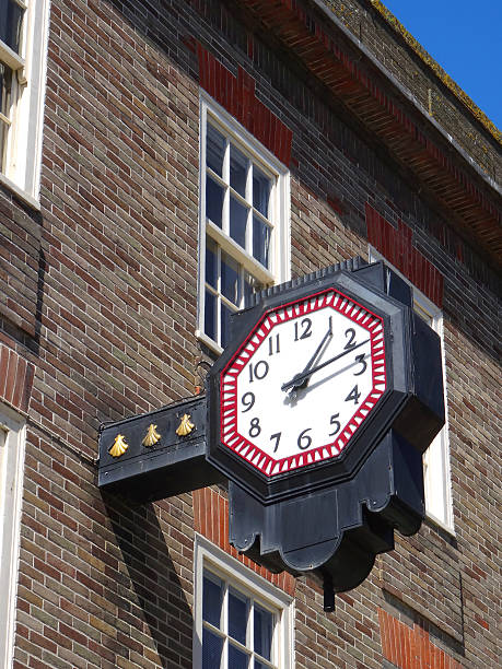 Image of numbered wall clock hanging above shop-front, town centre
