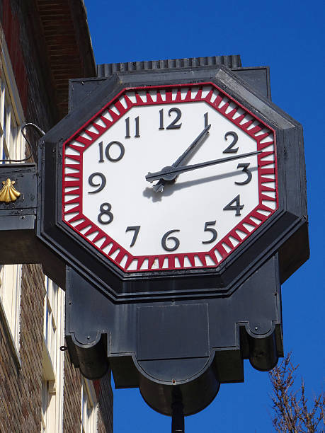 istock Image of octagonal metal clock hanging above shop, against sky 497827872