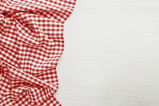Food background, high angle view of white wooden table with red, folded, checkered tablecloth copy space