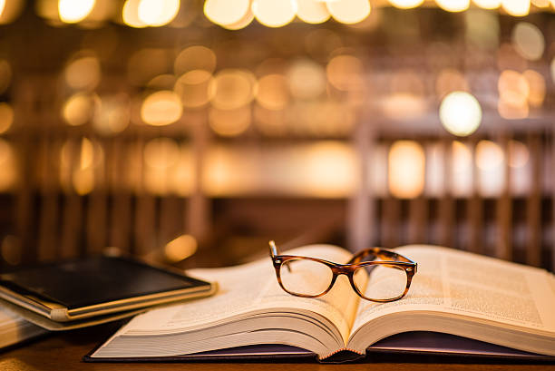 Reading glasses and digital tablet on book Close-up of reading glasses and digital tablet on book in library. reading glasses stock pictures, royalty-free photos & images