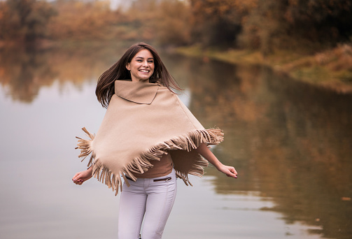 Carefree woman having fun during autumn day near the river.
