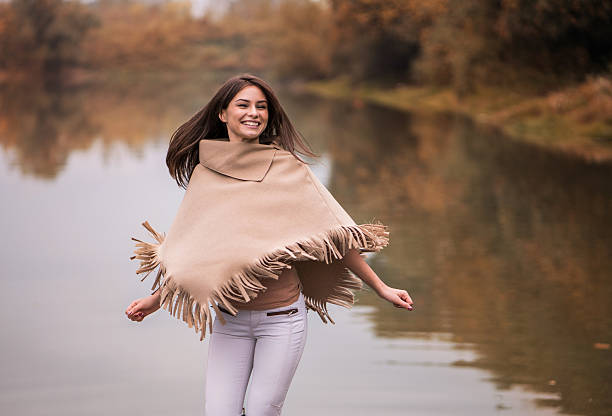 młoda szczęśliwa kobieta zabawy w pobliżu rzekę. - poncho zdjęcia i obrazy z banku zdjęć