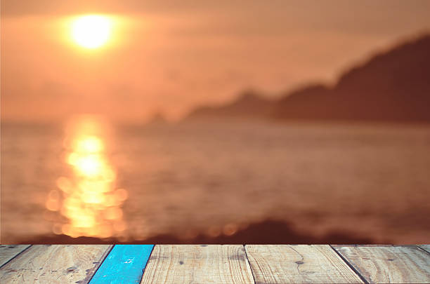istock Blur tropical sunset beach with old wood table background. 497829300