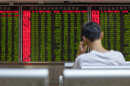 Beijing, China - August 24, 2015: Chinese citizen watching stock information at a Beijing open-to-the-public municipal access market trading exchange room facility during a stock market index decline in China.
