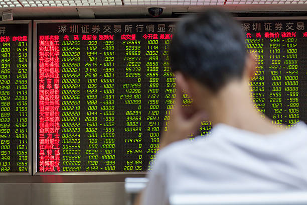Chinese Citizens Watching Stock Market, Beijing 2015 Beijing, China - August 24, 2015: Chinese citizen watching stock information at a Beijing open-to-the-public municipal access market trading exchange room facility during a stock market index decline in China. ticker tape machine stock pictures, royalty-free photos & images