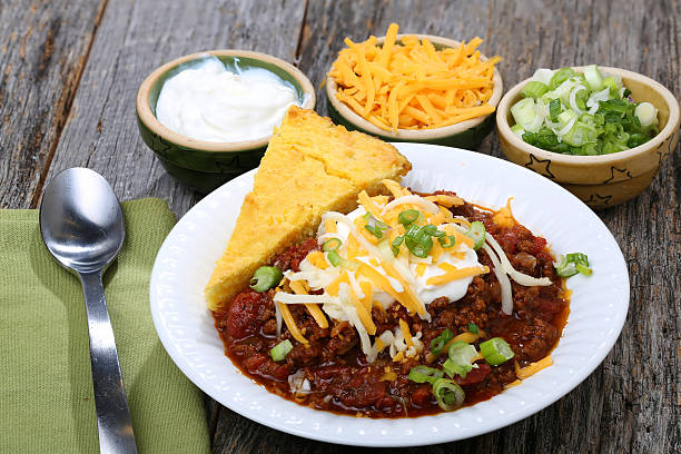 Chili with cornbread and fixings Tasty spicy chili con carne casserole in a pot for those winter nights, high angle view chili and cornbread stock pictures, royalty-free photos & images