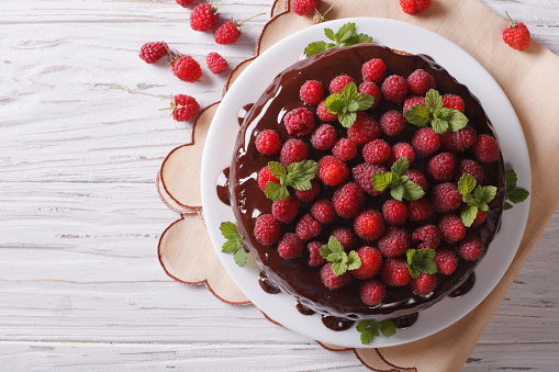 Chocolate cake with fresh raspberries and mint on the table. Horizontal top view
