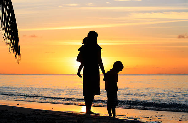 istock mother and two kids walking on beach at sunset 497832416
