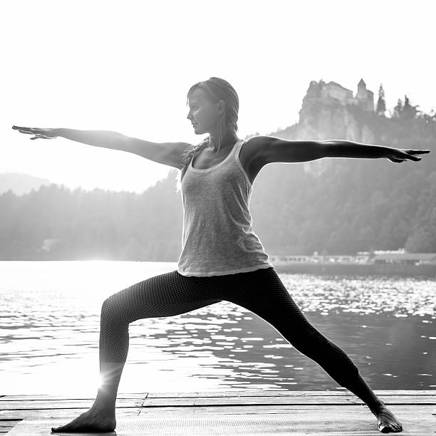 istock Yoga by the lake, warrior two position, black and white 497832590