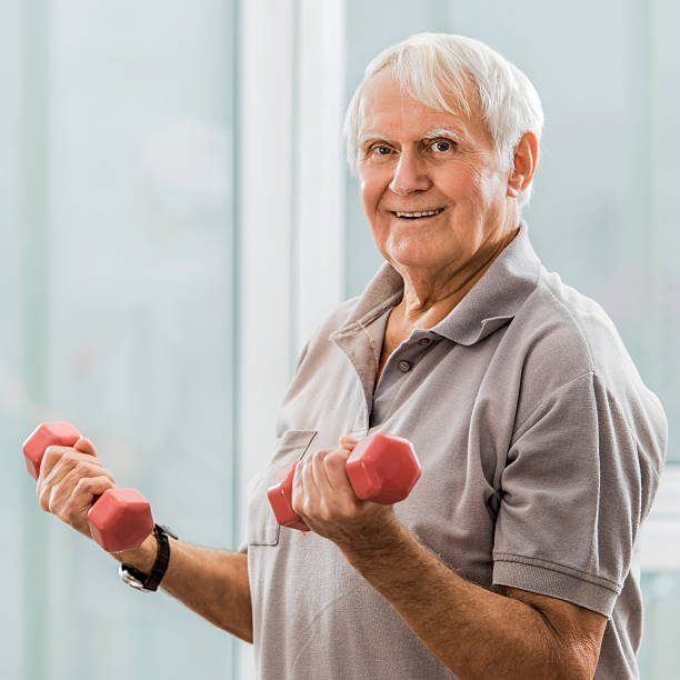 istock Smiling mature man exercising with dumbbells and looking at camera. 497832834