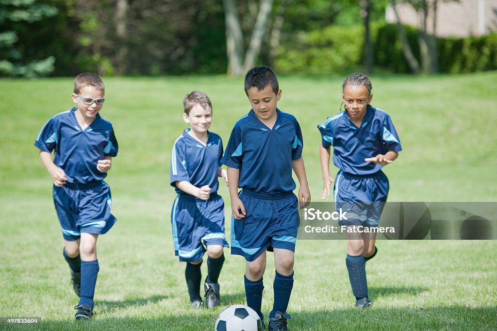 Children Kicking a Soccer Ball up the Field A multi-ethnic group of elementary age boys are running up the soccer field dribbling the soccer ball. Child Stock Photo