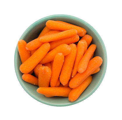 Top view of a large serving of organic small baby carrots in a green bowl isolated on a white background.