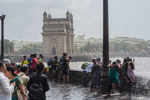 Mumbai_Waves_weather Mumbai, India - June 15, 2014: Big waves hitting the sea promenades when the weather turns towards monsoon in Mumbai. Kids getting splashed by the waves with Gateway of India in the background. mumbai photos stock pictures, royalty-free photos & images
