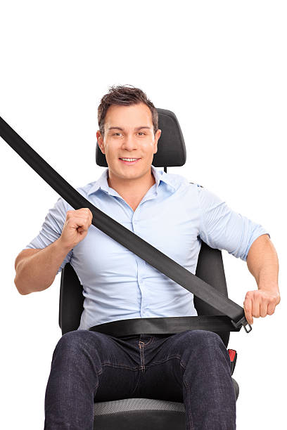 Man fastening his seat belt on a car seat Frontal vertical shot of a young man sitting on a car seat and fastening his seat belt isolated on white background seat belt photos stock pictures, royalty-free photos & images
