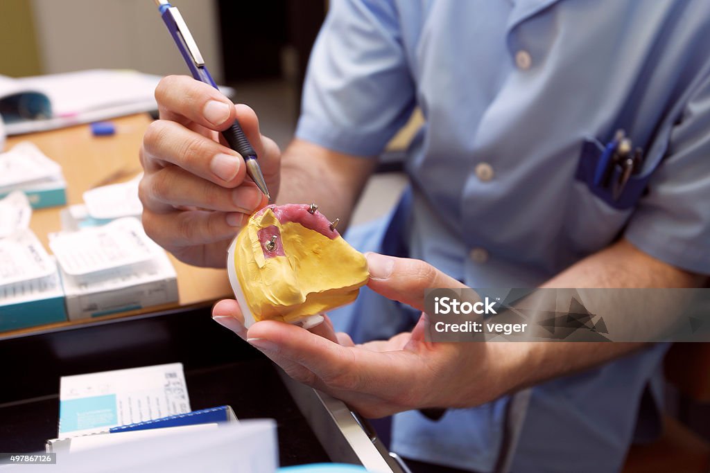 Dental prosthesis. Technician in dental lab demonstrating dental implant model. 2015 Stock Photo