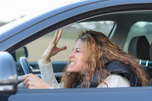 woman is driving her car very aggressive and gives gesture with his fist