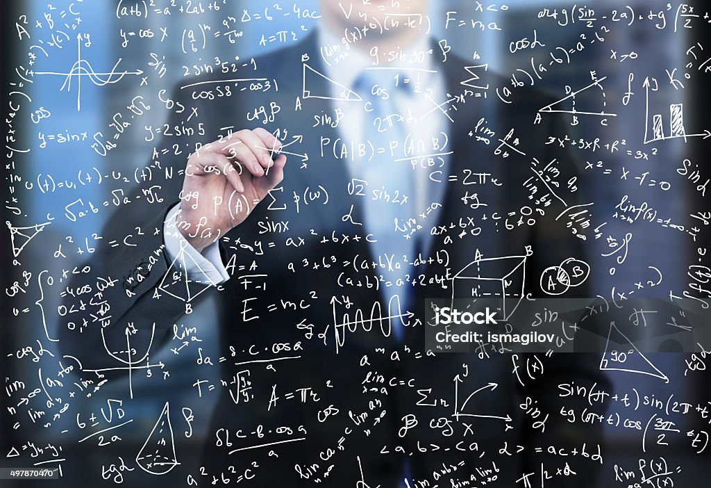 business person is writing down math formulas A business person is writing down math formulas on the glass screen in the evening modern panoramic office. Complexity Stock Photo