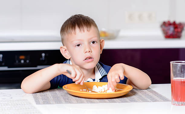 istock Boy Eating Last Bite of Food at Kitchen Table 497870658