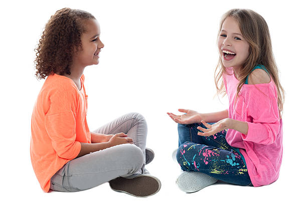 Calm pretty sisters sitting on carpet and playing with Easter eggs counting and passing them in living room