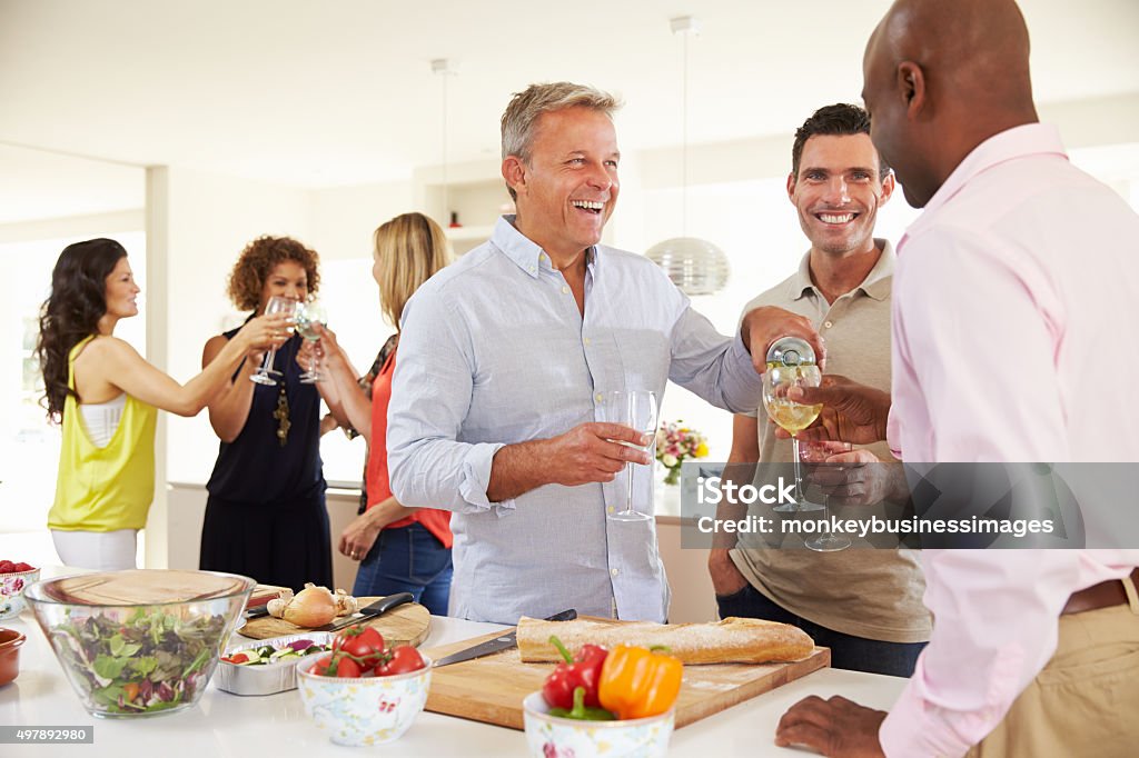 Group Of Mature Friends Enjoying Dinner Party At Home Dinner Party Stock Photo