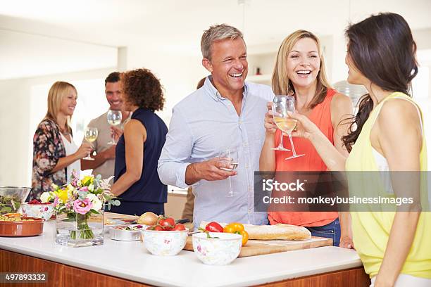 Mature Guests Being Welcomed At Dinner Party By Friends Stock Photo - Download Image Now