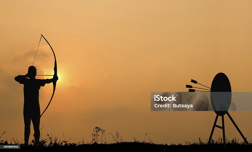 Silueta de tiro con arco dispara un arco en el objetivo. - Foto de stock de Tiro con arco libre de derechos