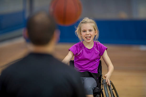 Little Girl in a Wheelchair A little girl in a wheelchair is bouncing a basketball to her therapist. leisure facilities stock pictures, royalty-free photos & images