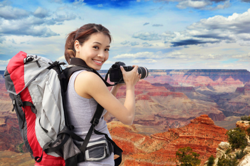 Young woman with backpack taking a photo in grand canyon, asian