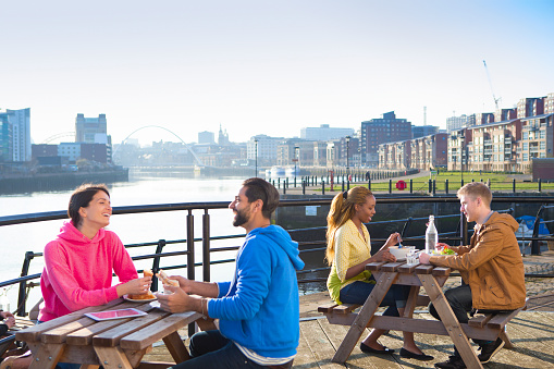 Two couples eat outside a cafe with the quayside in the background.