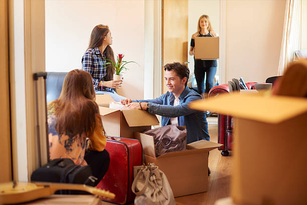 first day at university A group of four university students move into their shared flat , and start to unpack boxes. One male student is looking through his boxes in the foreground roommate stock pictures, royalty-free photos & images