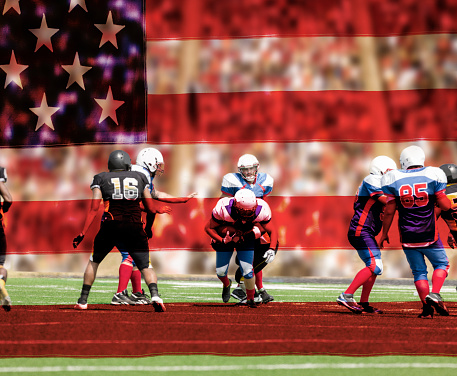 USA flag overlayed on image of semi-professional football team's running back carries the football to make a play. Defenders try to tackle him. Football field with a stadium full of unrecognizable fans in background.