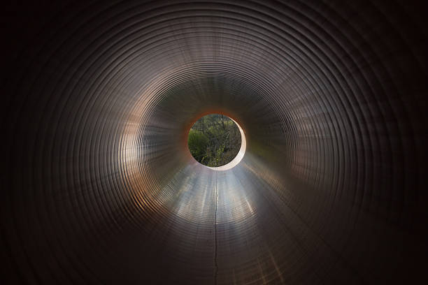 Inside view of a huge pipe tube on a pipeline construction. Light enters through the pipe.