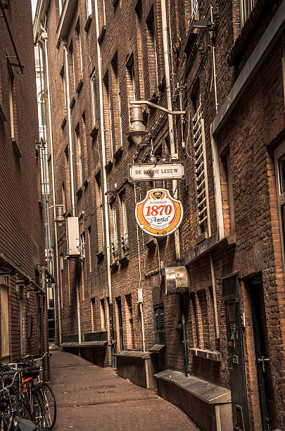 gasse mit amstel bier zeichen - editorial outdoors vertical amsterdam stock-fotos und bilder