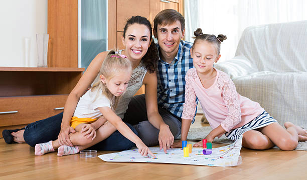 istock girls playing with parents at board game on floor 497940576