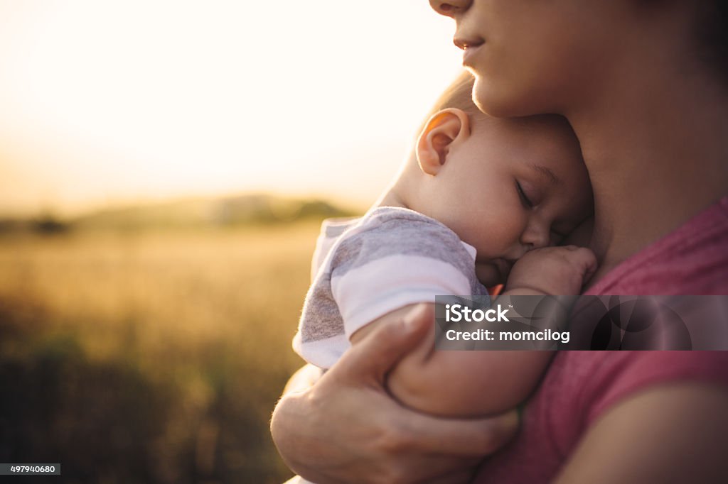 Nap time Mother hugging sleepy son at the gold field Baby - Human Age Stock Photo