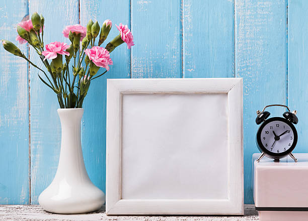 istock Blank white frame, pink flowers and alarm clock 497942794