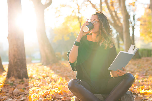 istock Young woman reading in the park,drinking coffee 497943562