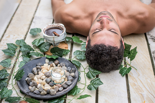 Handsome Latin American man relaxing at the spa and getting a massage with chocolate