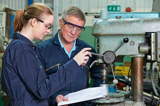 istock Engineer Showing Female Apprentice How To Use Drill In Factory 497947203