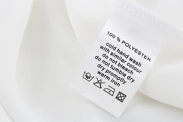 Fabric composition and washing instructions label on white shirt Fabric composition and washing instructions label on white shirt polyester photos stock pictures, royalty-free photos & images
