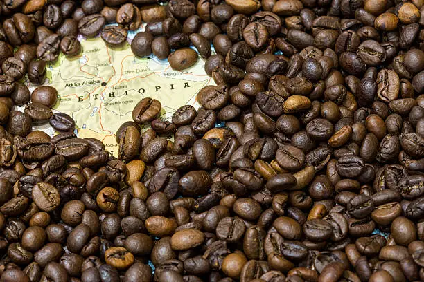 Geographical map of Ethiopia covered by a background of roasted coffee beans. This nation is between the five main producers and exporters of coffee. Horizontal image.