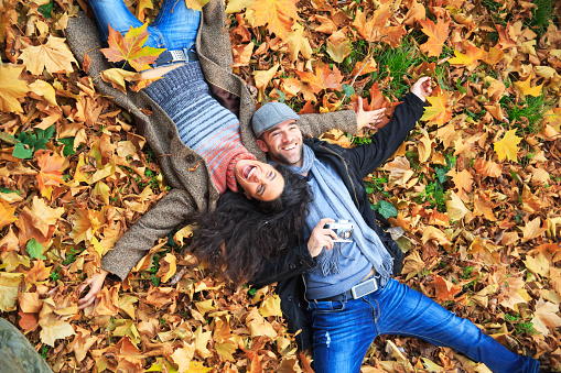 Smiling couple lying down on leaves